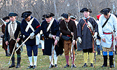 The minutemen lower their muskets after firing a salute.